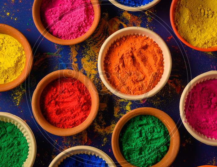 top view of colorful traditional holi powder in bowls isolated on dark background.Space for text . happy holi.Concept Indian color festival called Holi