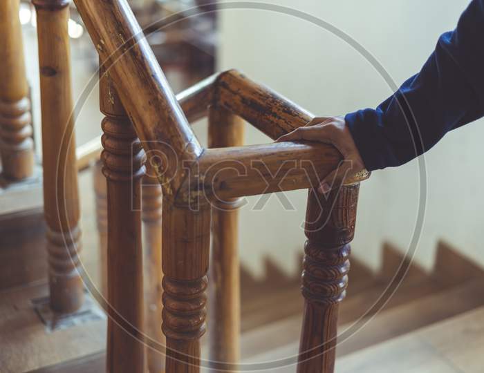 Support, Help And People Concept- Close Up Of A Man'S Hand Holding To A Wooden Railing While Climbing A Staircase.