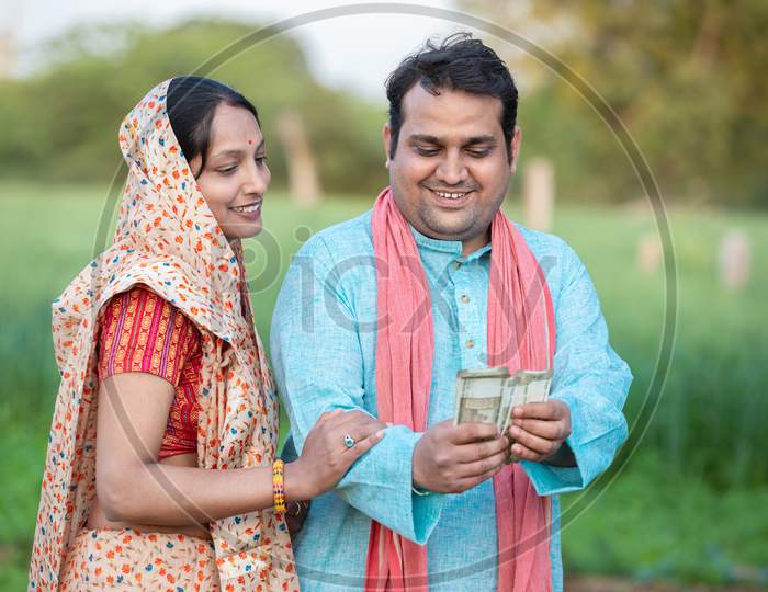 Happy Indian Farmer Couple Counting Rupees Note At Agriculture Field, Man Holding Money.