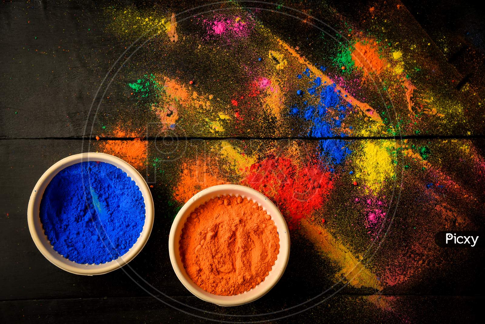 top view of colorful traditional holi powder in bowls isolated on dark background.Space for text . happy holi.Concept Indian color festival called Holi