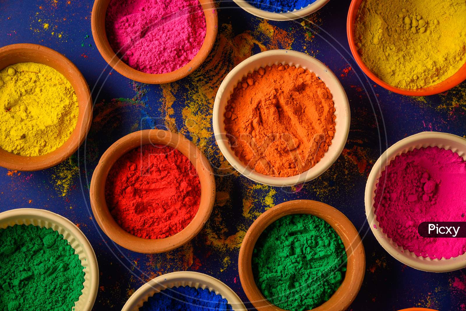 top view of colorful traditional holi powder in bowls isolated on dark background.Space for text . happy holi.Concept Indian color festival called Holi