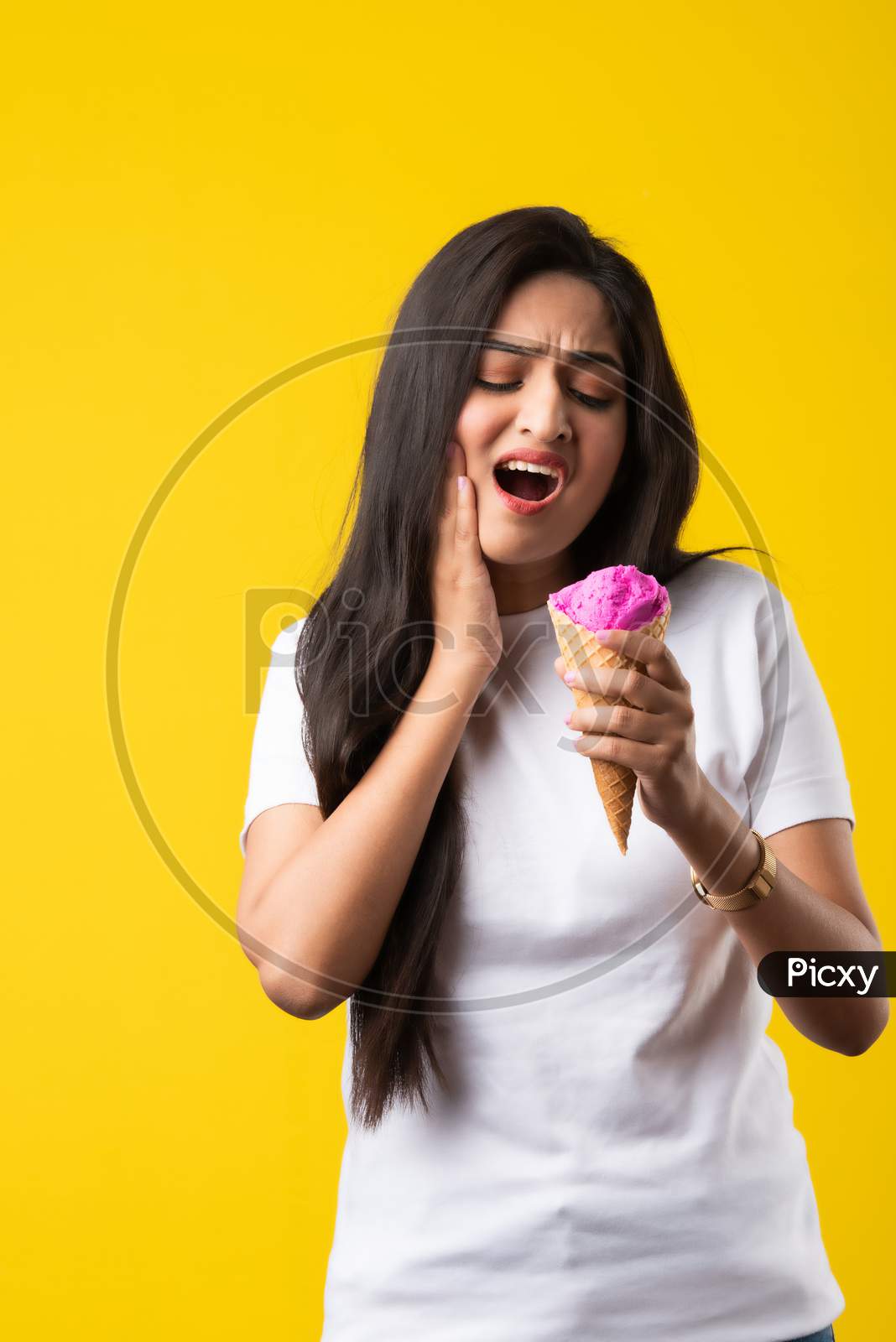 Pretty Young Indian Woman With Sensitive Teeth And Eating Cold Ice Cream On Yellow Background