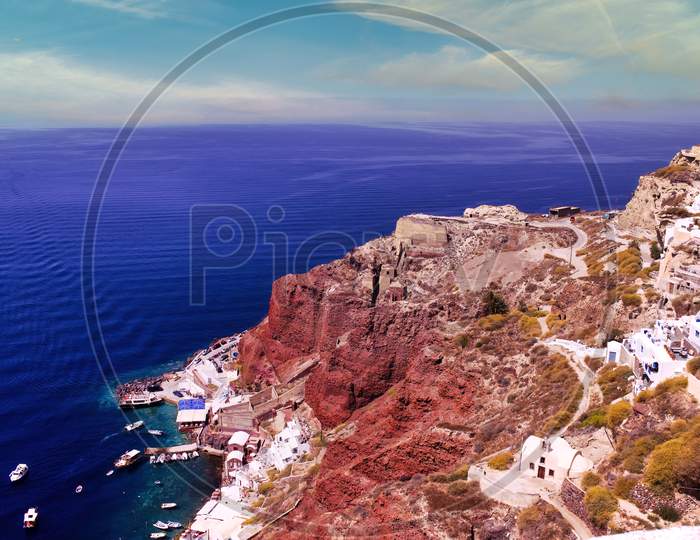 Santorini, Greece: Beautiful City Of Oia ( Ia ) On A Hill With Blue Roof During Day Time, Located In Greek Cyclades Islands Against Mediterranean Sea