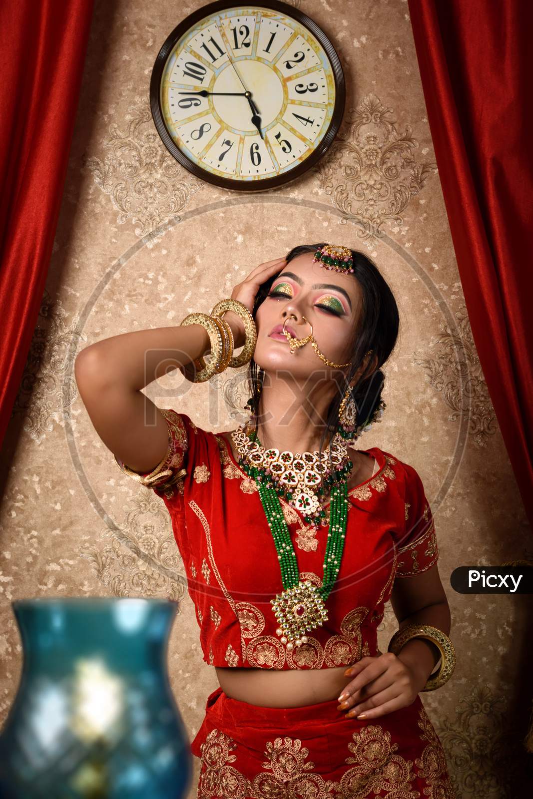 Portrait Of Very Beautiful Young Attractive Indian Bride In Luxurious Bridal Costume With Makeup And Heavy Jewellery In Studio Lighting Indoor. Wedding Fashion.
