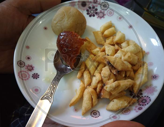Indian Sweets And Snacks Serving In A Plate With A Spoon Holding With Hand Selectively Focused.
