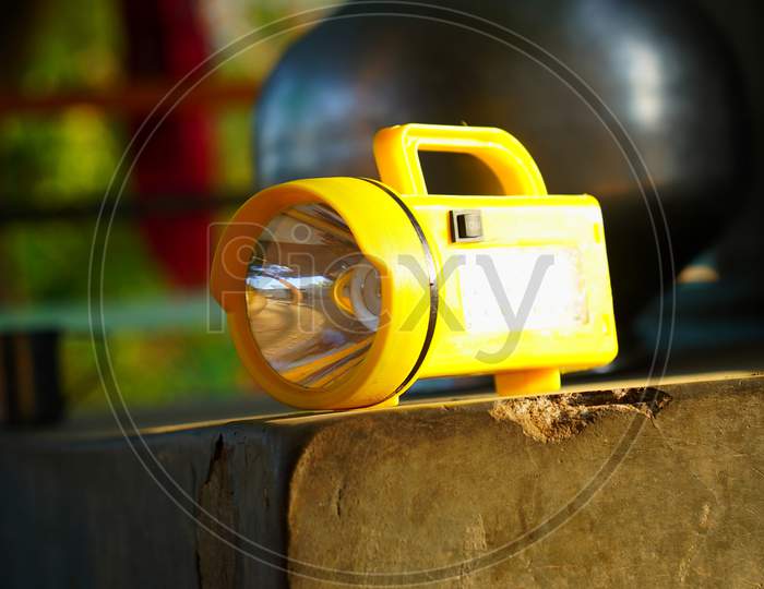 Closeup Shot Of Yellow Battery On The Rough Column. Electric Chargeable Search Light Torch With Handle.