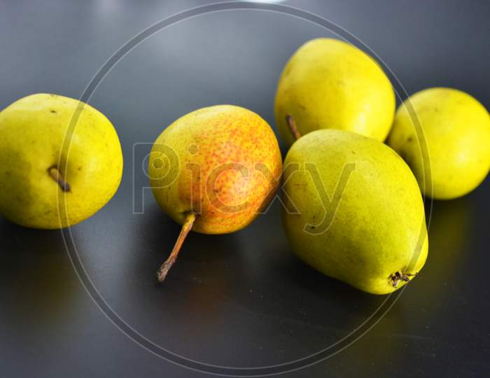 Bright tasty juicy pears of green, red and yellow color are located on a black plastic background. Proper nutrition, healthy fresh fruits for every day.