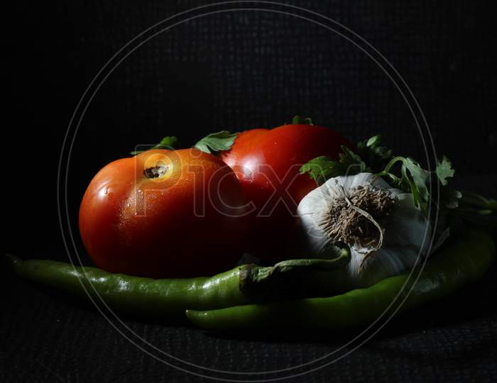 Green Chilly, Garlic, Onion, Tomato And Curry Leaf Are Isolated On Black Background. Ingredients Concept. Hot And Spicy Green Chilies And Fresh Ripe Tomato On Black Background.