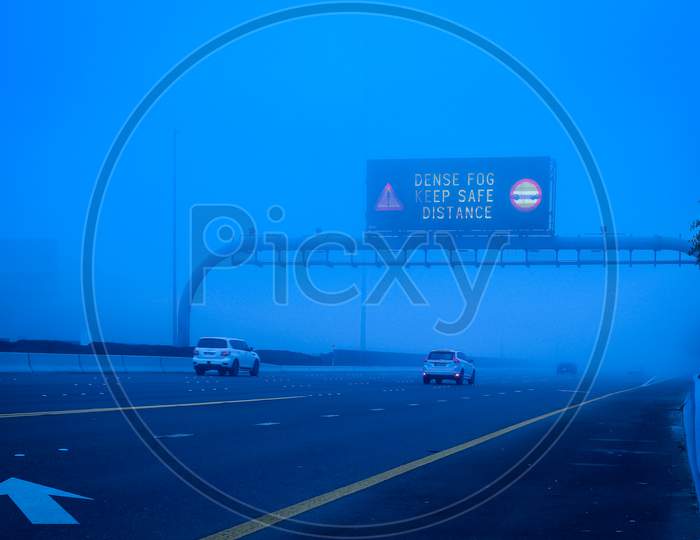 Road In The Fog, Sign Mention Keep Distance For Motorists At Dubai Road, Foggy Weather In Uae, Dense Fog Keep Safe Distance Banner In Arabic And English
