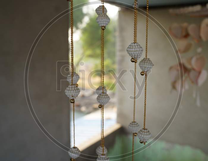White Ceramic Bells On The Background Of The Door. Bells Close-Up. Door Hanging Or Decorations Closeup.