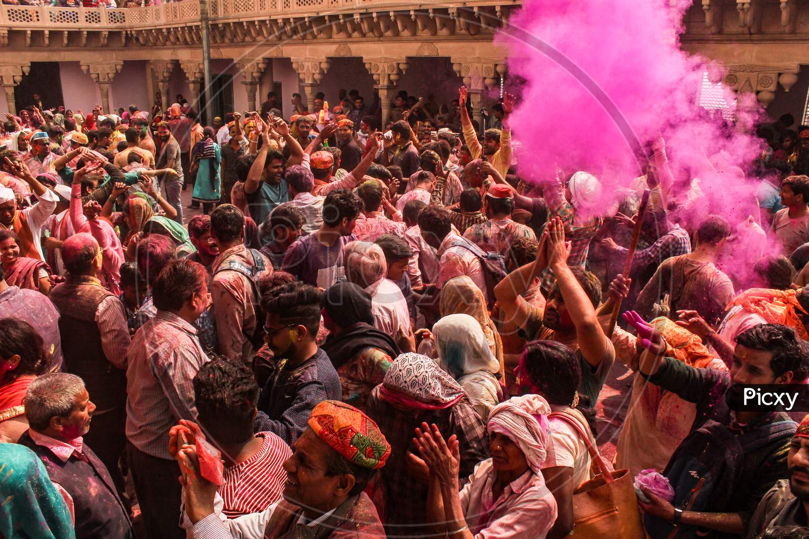 Mathura, Uttar Pradesh/ India- January 6 2020: People Throw Colors To Each Other Wearing Traditional Clothes Holding Stick During The Holi Celebration At Krishna. Temple. Young People Having Fun At The Festival Of Colour.