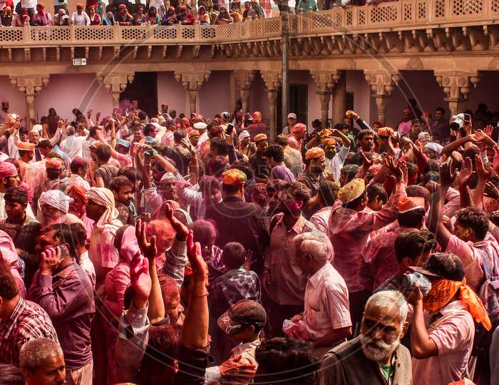 Mathura, Uttar Pradesh/ India- January 6 2020: People Throw Colors To Each Other Wearing Traditional Clothes Holding Stick During The Holi Celebration At Krishna. Temple. Young People Having Fun At The Festival Of Colour.