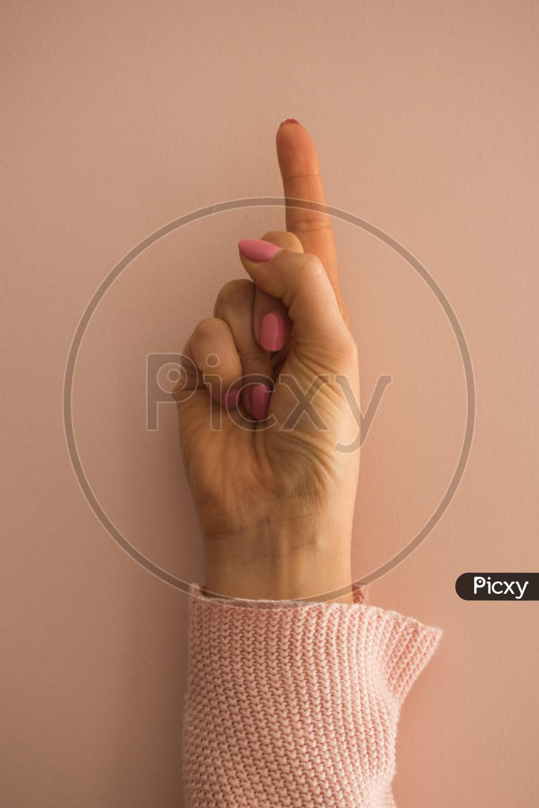 A Female Hand With The Index Finger Pointing Up