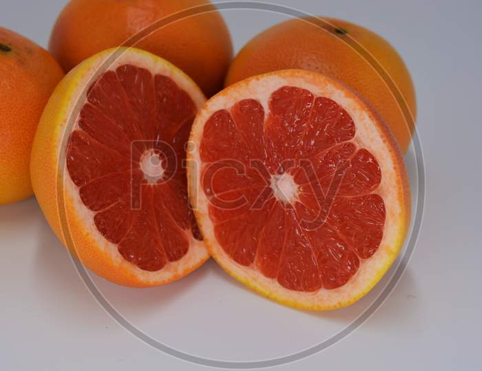 Two halves of a ripe juicy grapefruit, divided into two identical halves, located on a white background. Delicious and healthy sweet and sour fruits for the human body and health.