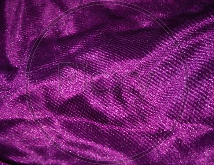 Bright colorful, rich velvet purple background with overflow and ebb. An unusual shaggy purple fabric with curves and waves is located on a flat surface, an unusual look.