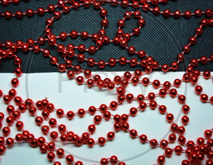 New Year and Christmas red beads for the New Year tree are randomly scattered on white and black fabric backgrounds.