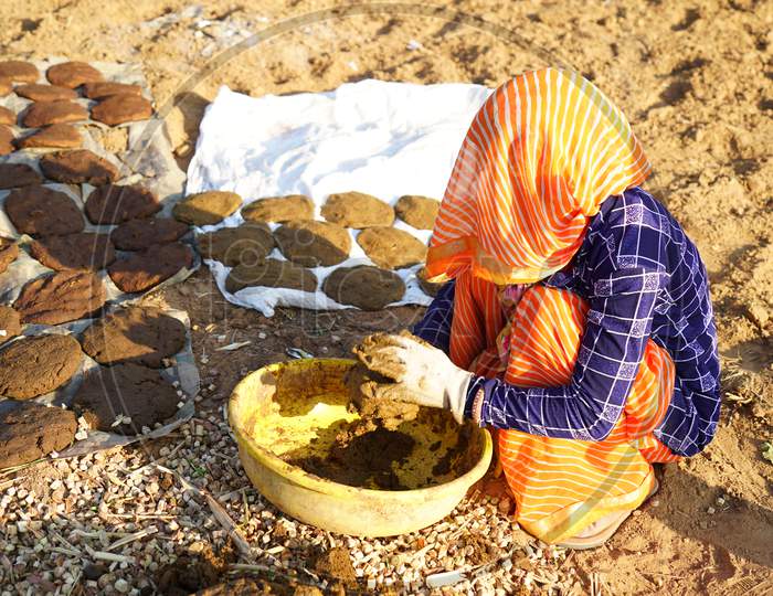 Indian Woman Preparing Cow Dung And Making Dung Cakes For Sacred Festivals. Religious Culture To Make Cow Dung Cakes On Holi Festival In Hindu Religion.