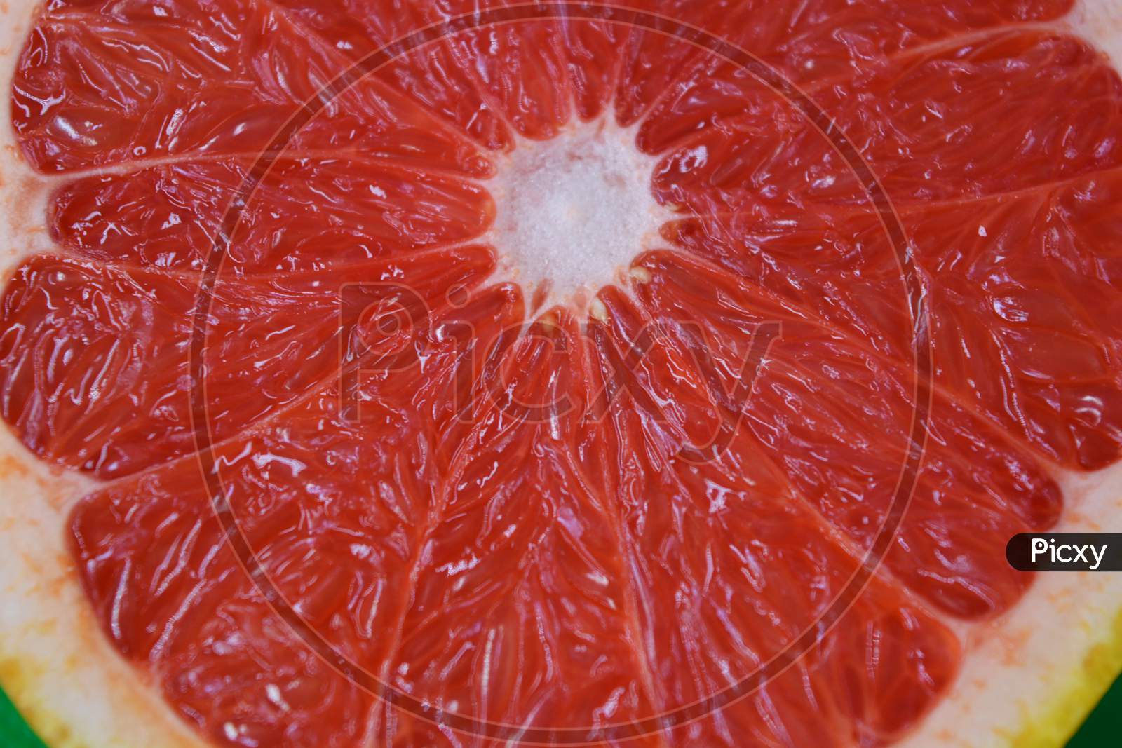 Ripe and tasty fruits, fresh grapefruit cut in half, sliced grapefruit set on a green fabric background.