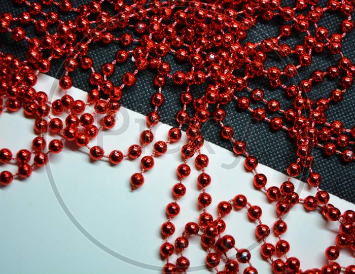 New Year and Christmas red beads for the New Year tree are randomly scattered on white and black fabric backgrounds.
