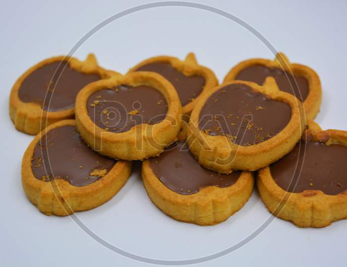 Fresh delicious crunchy shortbread cookies with nutty, chocolate filling inside. Apple-shaped cookies with brown filling located on a white matte background.