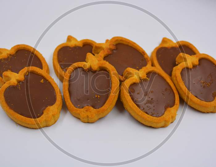 Fresh delicious crunchy shortbread cookies with nutty, chocolate filling inside. Apple-shaped cookies with brown filling located on a white matte background.