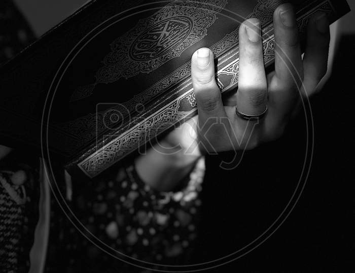 A Woman Reading The Quran On A Prayer Rug