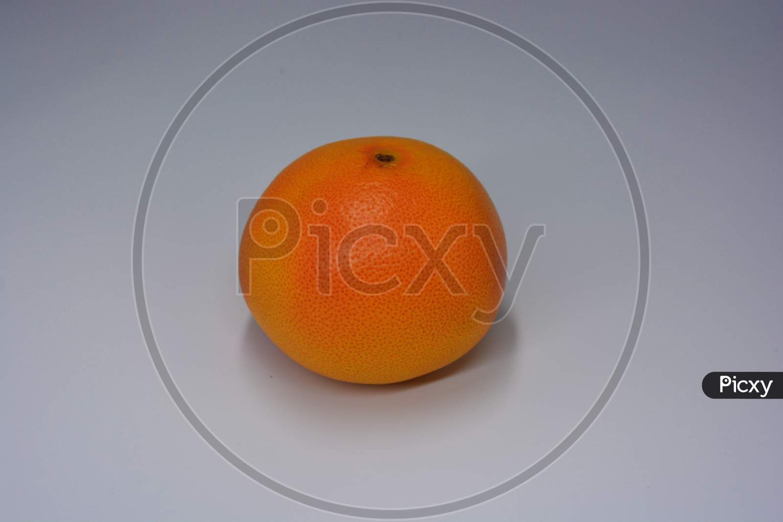 One big ripe delicious orange-red grapefruit arranged on a white plate. Delicious and healthy sweet and sour fruits for the human body and health.