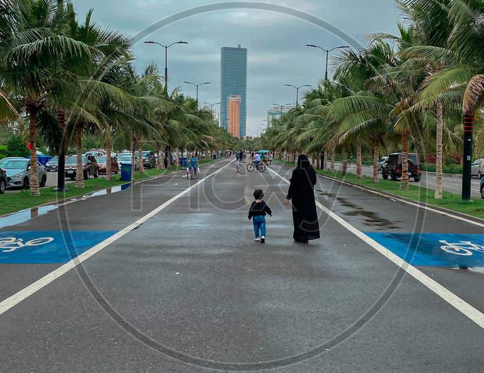 A Woman Walking With A Child On Road In Corniche, Jeddah, Saudi Arabia, 2021
