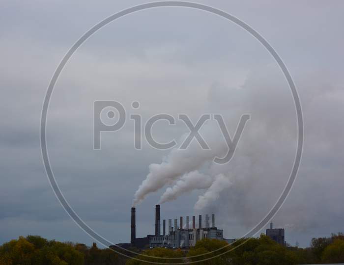 Pollution of the environment, air and water, harmful emissions into the urban atmosphere of the city of Kamianske. Hazy white gray brown steam is piped into the sky from a large plant.