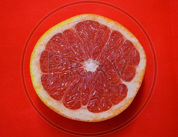 Halves of ripe juicy grapefruit, divided in half, placed on a red fabric background. Delicious and healthy sweet and sour fruits for the human body and health.