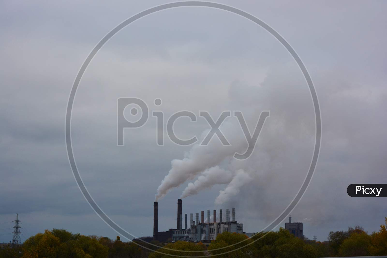 Pollution of the environment, air and water, harmful emissions into the urban atmosphere of the city of Kamianske. Hazy white gray brown steam is piped into the sky from a large plant.