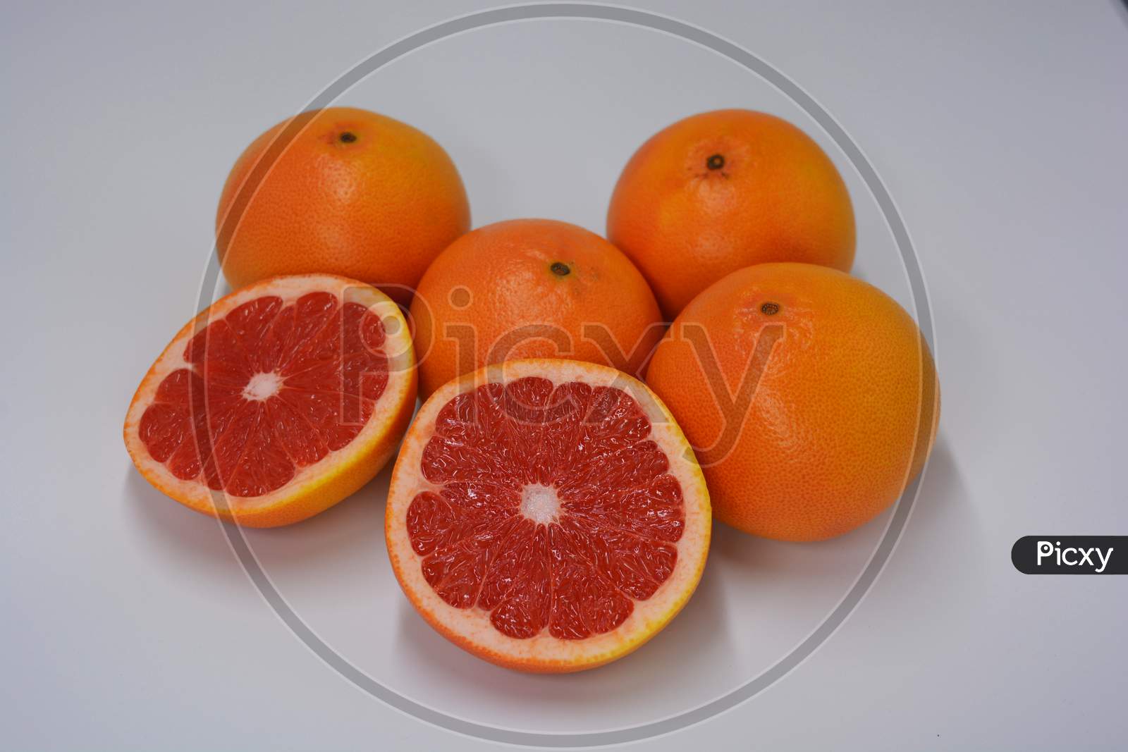 Two halves of a ripe juicy grapefruit, divided into two identical halves, located on a white background. Delicious and healthy sweet and sour fruits for the human body and health.