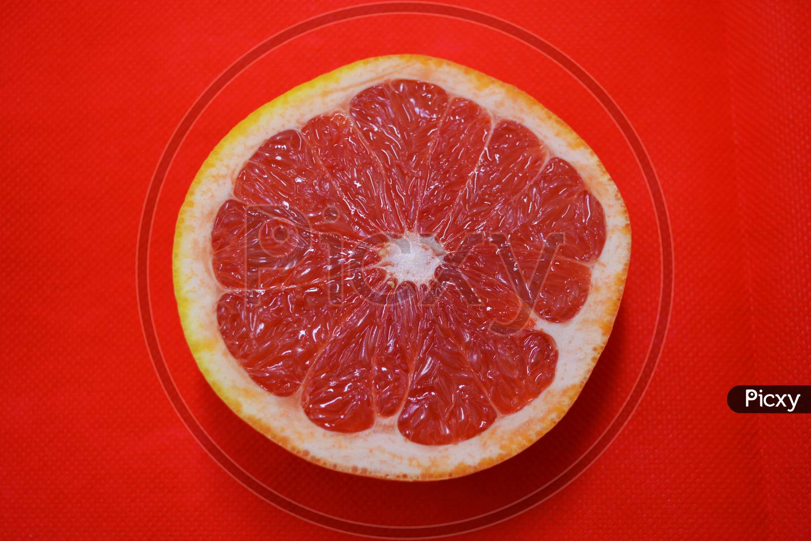 Halves of ripe juicy grapefruit, divided in half, placed on a red fabric background. Delicious and healthy sweet and sour fruits for the human body and health.