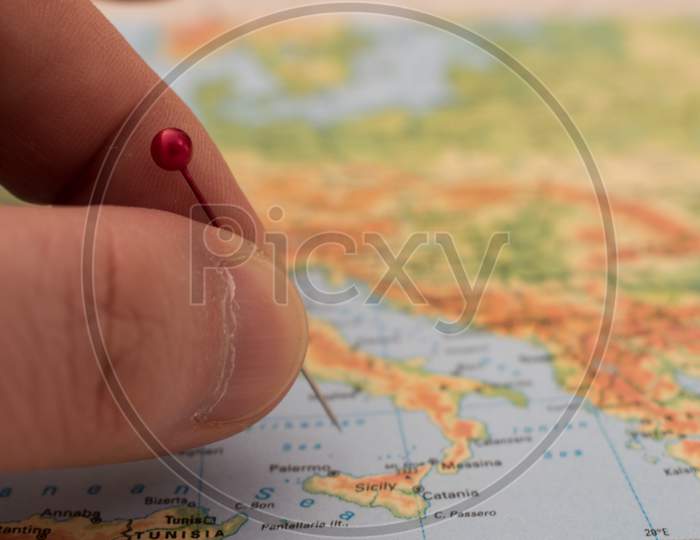 Close Up On A Hand Placing A Pin On A Map