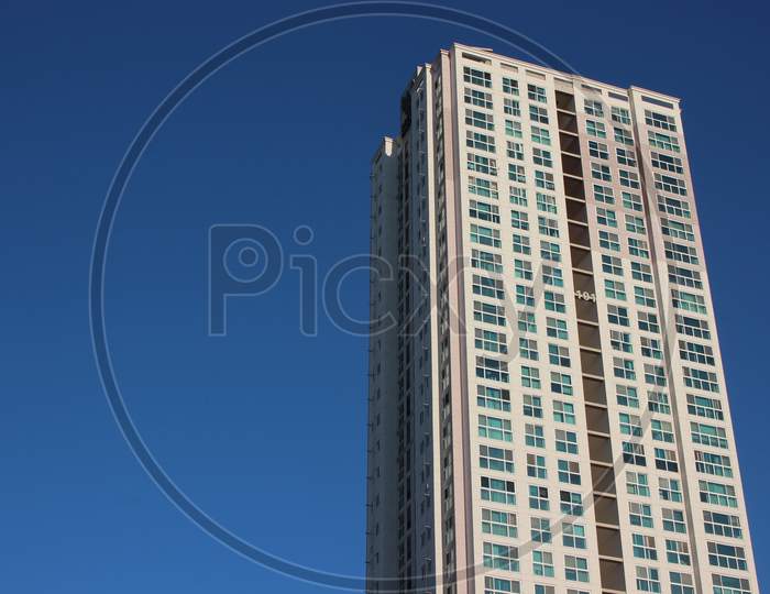 The Wide-Angle View Of A Skyscraper Commercial Building With Blue Sky On Sunny Day.