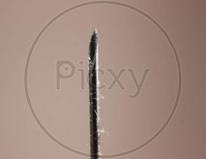 Water Drop Falling From The Syringe Needle Against Grey Background