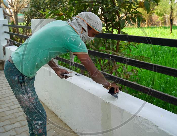 Young Professional Indian Painter Doing Paint On Wall. Painting Renovation And Young Man Doing Paint With Roller.