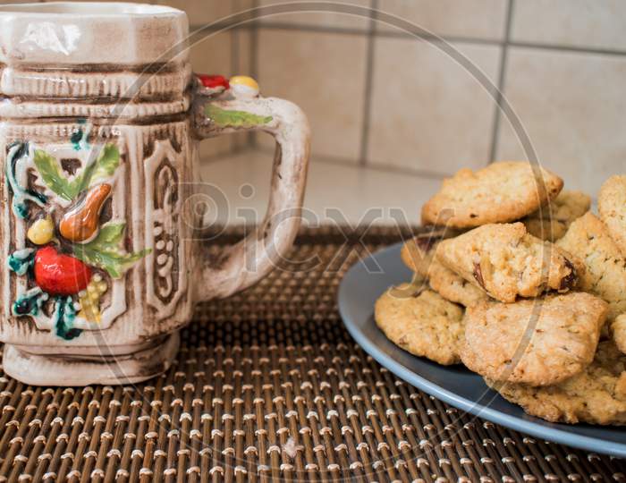 A Plate With Chocolate Chips Cookies And A Colorful Mug
