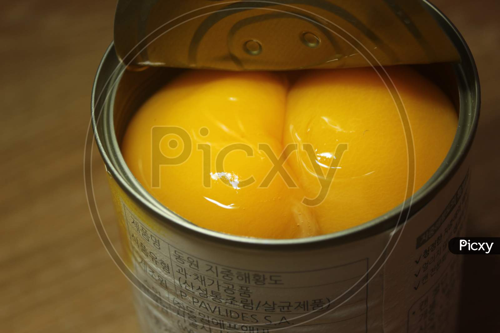 Canned Peaches Halves Sprinkled With Syrup In A Metallic Can On Wooden Floor