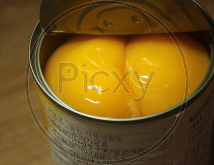 Canned Peaches Halves Sprinkled With Syrup In A Metallic Can On Wooden Floor