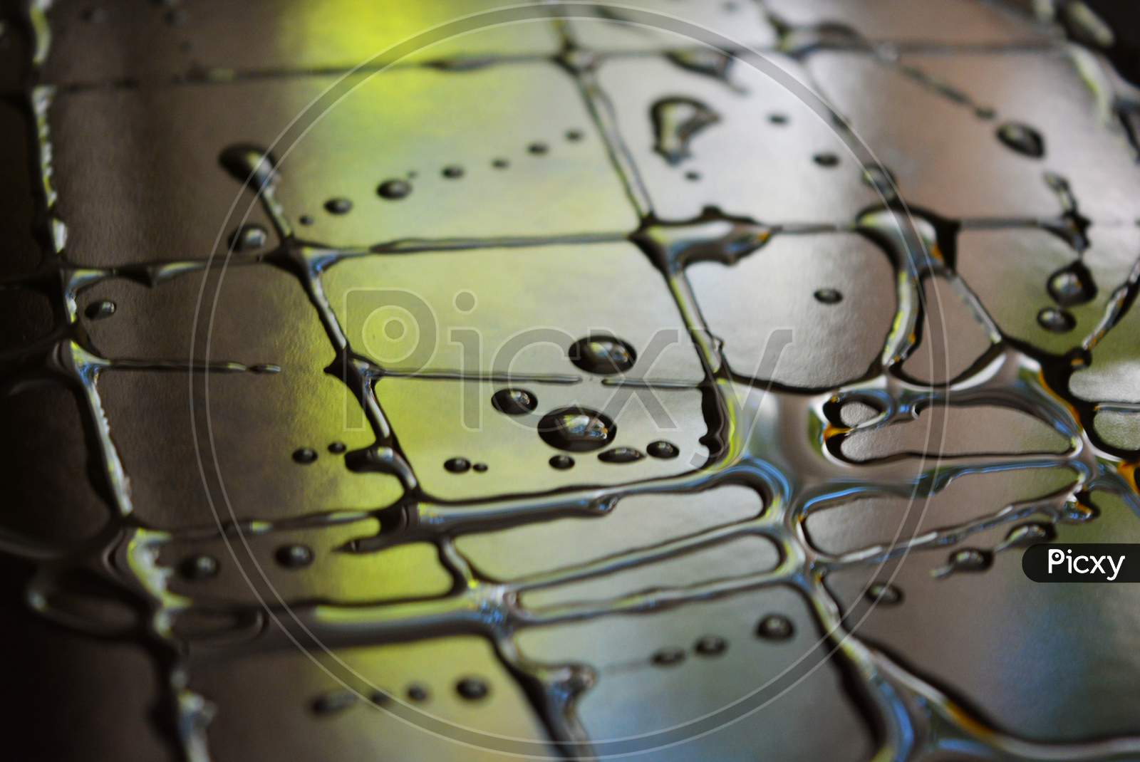 Water and oil droplets in the form of art inscriptions on a black metal surface with light reflections. Unusual abstract background, art and light painting.