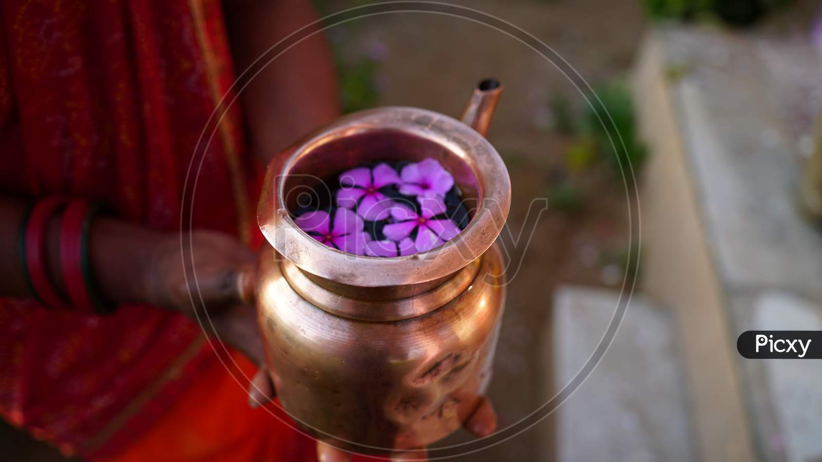 Closeup Shot Of Copper Kalash Filled With Sacred Water To Offer God. Human Hand Holding Kalash To Religious Morning Prayer.