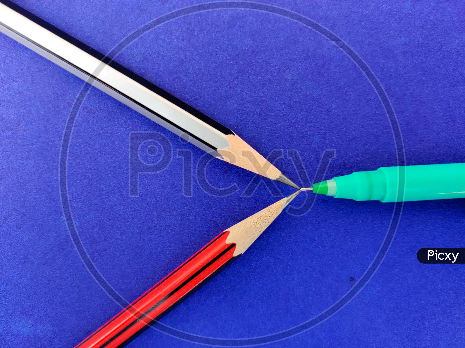 Two Pencil And Pen Pointing Each Other Isolated On Blue Background
