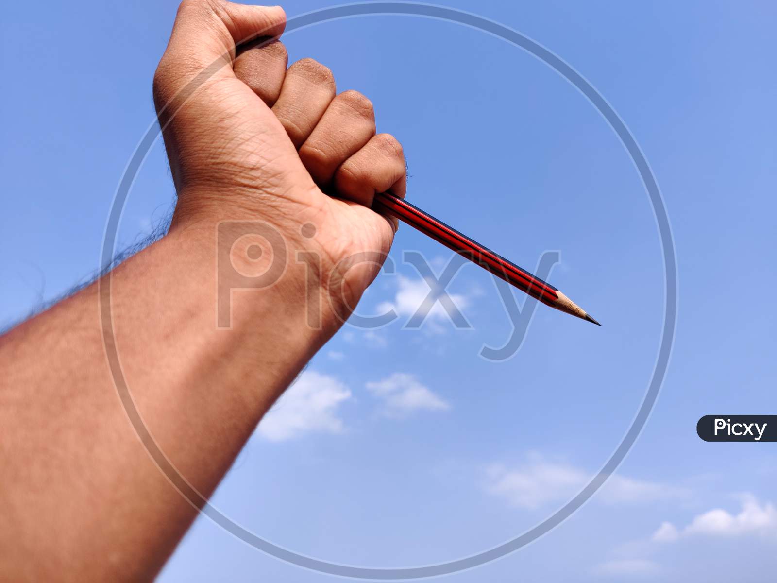 South Indian Man Hand Holding Sharp Red Color Pencil. Isolated On Cloud Background