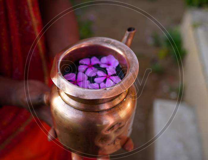 Closeup Shot Of Copper Kalash Filled With Sacred Water To Offer God. Human Hand Holding Kalash To Religious Morning Prayer.