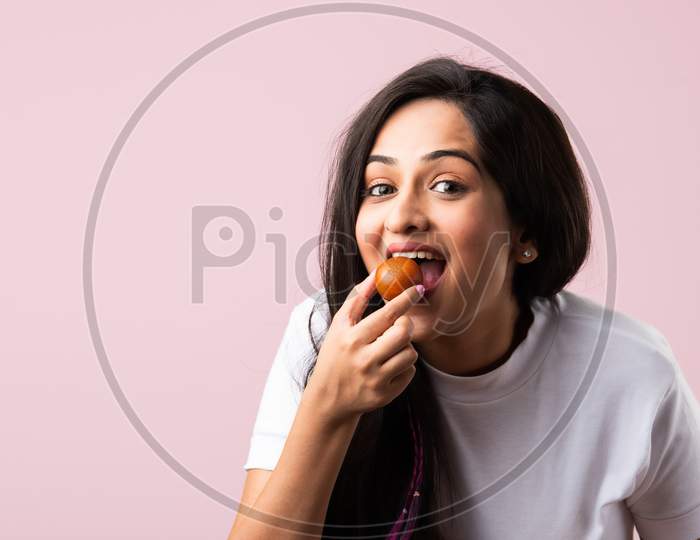 Indian Asian Pretty Young Woman Eating Gulab Jamun Sweet Food With Spoon