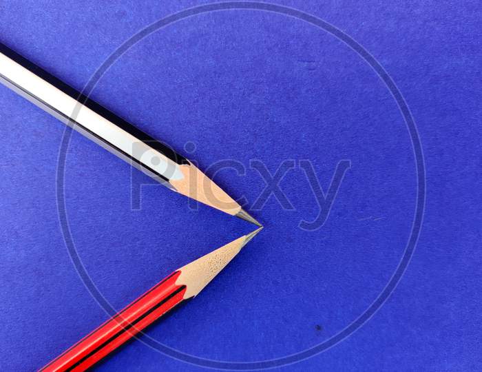 Copy Space Of Red And Black Color Pencil Pointing Each Other On Blue Background