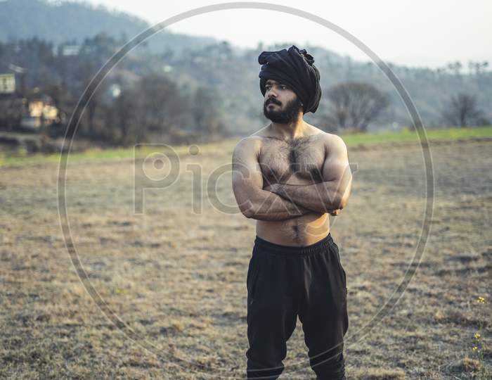 Young Indian Farmer With A Turban Standing On A Wasteland Field. Crops Not Growing Due To Shortage Of Rain And Water.