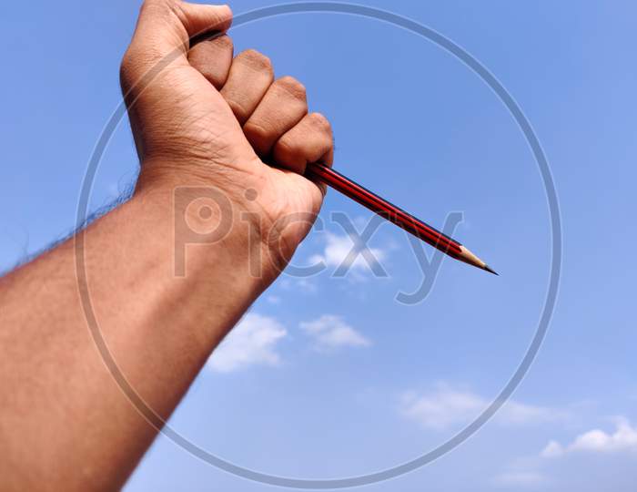 South Indian Man Hand Holding Sharp Red Color Pencil. Isolated On Cloud Background