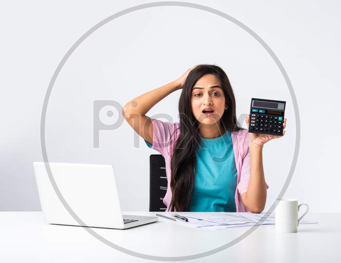 Young Indian Pretty Girl Accounting With Papers, Laptop And Calculator At Desk